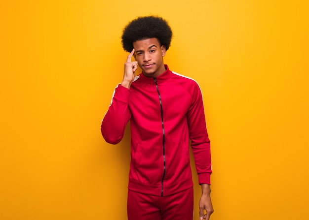 Photo jeune homme noir au-dessus d'un mur orange pensant à une idée