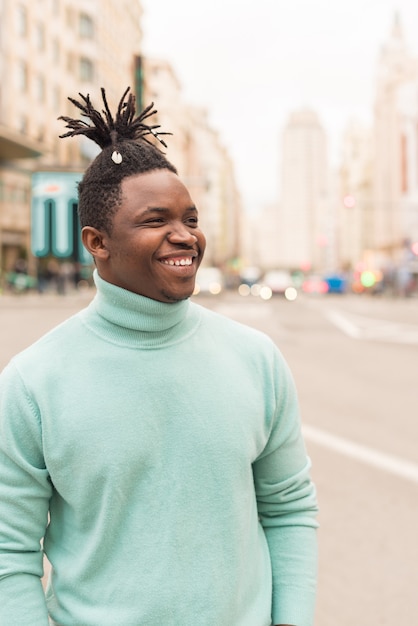 Jeune homme noir au milieu de la ville, souriant. Mise au point sélective.