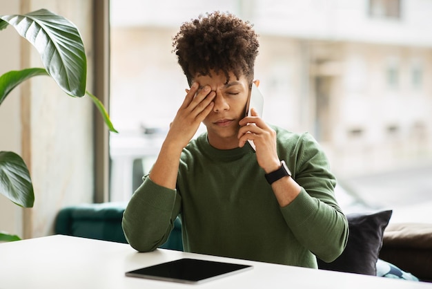 Photo un jeune homme noir malheureux a une conversation téléphonique au café