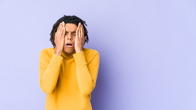 Jeune homme noir portant une coiffure rasta pleurnichant et pleurant de façon inconsolable.