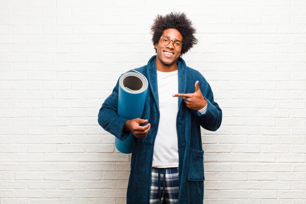 Jeune homme noir portant un pyjama avec un tapis de yoga