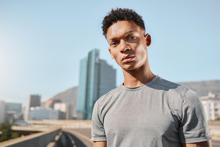 Photo jeune homme noir et portrait sur le pont avec le ciel des bâtiments et la ville pour courir fitness et entraînement de l'homme dans le métro urbain ou la ville sous le soleil d'été dans la rue avec un rêve de vision ou un objectif