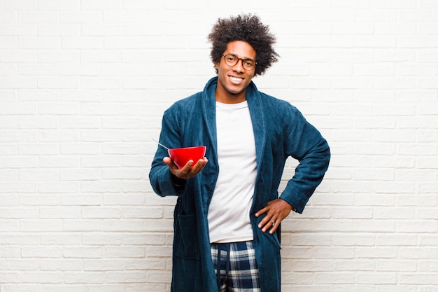 Jeune homme noir en pyjama avec un bol de petit-déjeuner