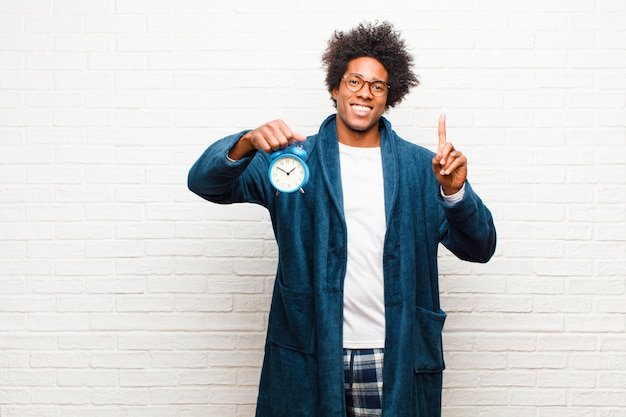 Photo jeune homme noir en pyjama avec réveil