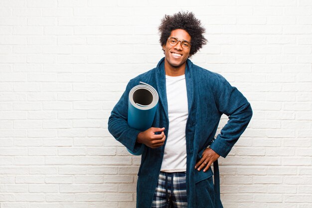 Jeune homme noir en pyjama avec un tapis de yoga