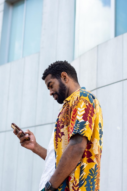 Jeune homme noir avec un smartphone dans la rue