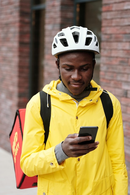 Jeune homme noir souriant en casque et veste jaune