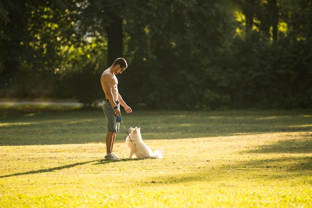 Jeune homme nu tenant un chien Spitz allemand dans le parc ensemble en profitant de la vue