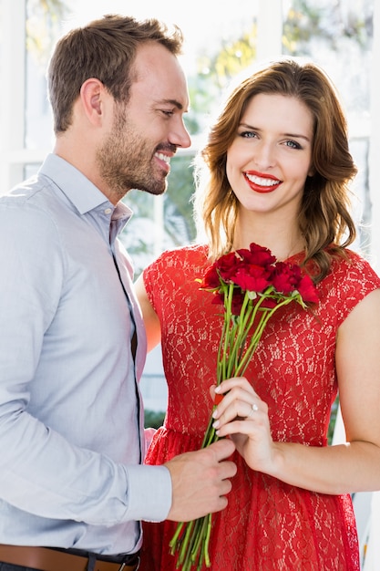 Jeune homme offrant un bouquet de fleurs à une belle femme