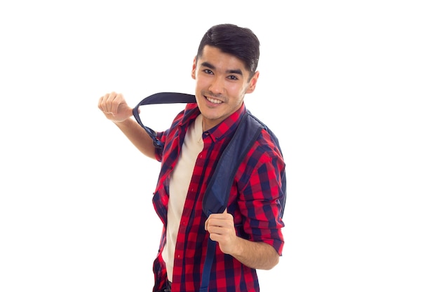 Jeune homme optimiste aux cheveux noirs en jeans Tshirt blanc et chemise à carreaux rouge avec sac à dos