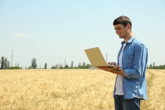 Jeune homme avec ordinateur portable dans le champ d'orge