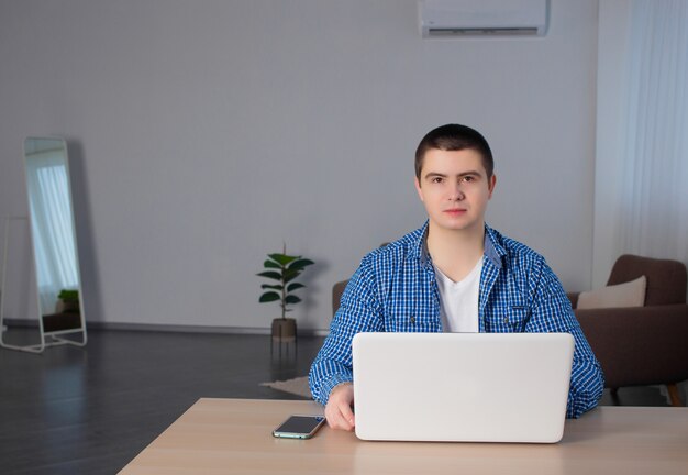 Jeune homme avec ordinateur portable est assis à un bureau dans le bureau. Testeur ou concepteur web au travail