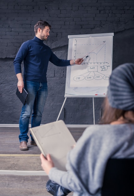 Jeune homme parlant au public montrant un graphique sur un tableau à feuilles mobiles