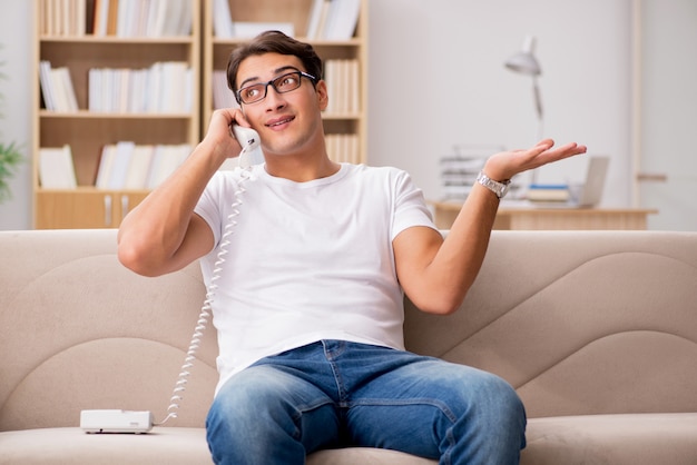 Jeune homme parlant au téléphone allongé sur un canapé