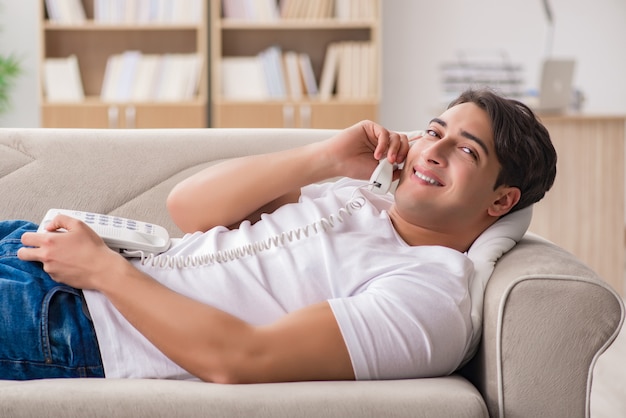 Jeune homme parlant au téléphone allongé sur un canapé