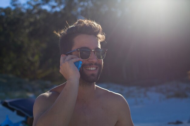 jeune homme parlant au téléphone à la plage