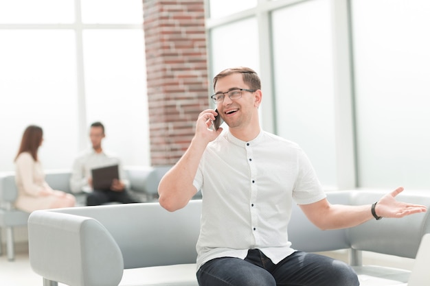 Jeune homme parlant sur un téléphone portable dans le hall du centre d'affaires. concept d'entreprise