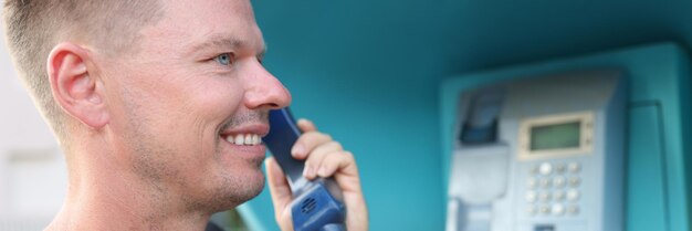 Jeune homme parle au téléphone au concept de répartiteur d'appels de cabine téléphonique