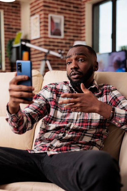 Jeune homme participant à une conférence vidéo en ligne, utilisant une application pour smartphone pour parler aux personnes lors d'un appel par vidéoconférence. Freelancer discutant lors d'une réunion d'affaires par téléconférence à distance sur téléphone mobile.