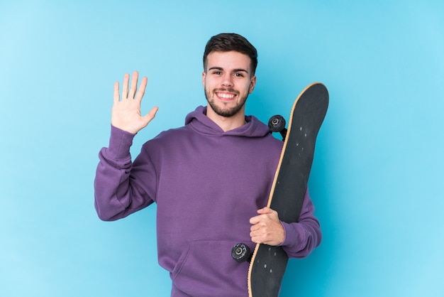 Jeune homme patineur isolé souriant joyeux montrant le numéro cinq avec les doigts