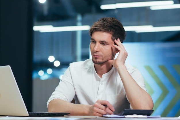 Jeune homme pensant au bureau homme d'affaires travaillant avec un ordinateur portable sur le plan d'affaires et la stratégie de développement de démarrage