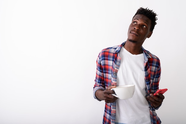 Jeune homme pensant tout en tenant une tasse de café