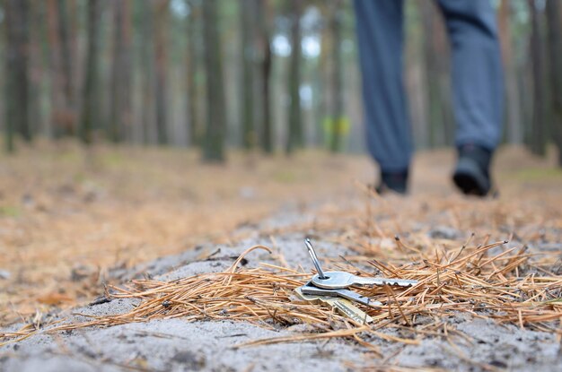 Jeune homme perd son trousseau de clés sur le chemin du bois de sapin d'automne russe Insouciance et concept de perte de clés