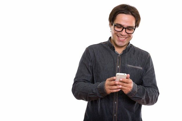 Jeune homme persan heureux souriant tout en utilisant un téléphone mobile