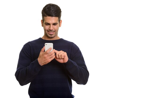 Jeune homme persan heureux souriant et utilisant un téléphone mobile