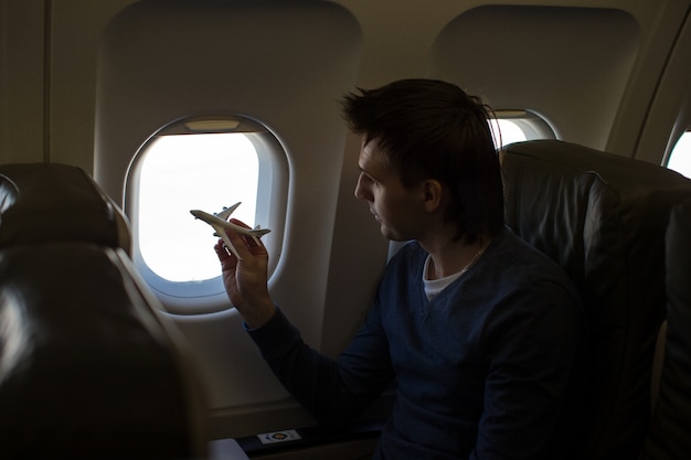 Jeune homme avec petit modèle d'avion à l'intérieur d'un gros avion