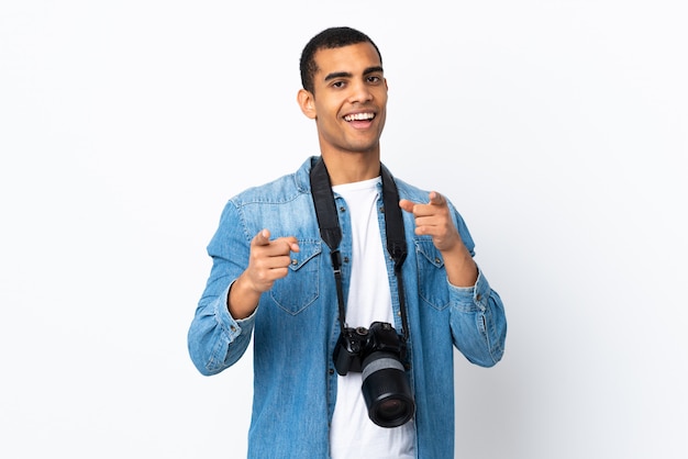 Jeune homme photographe afro-américain sur un mur blanc isolé pointe le doigt vers vous