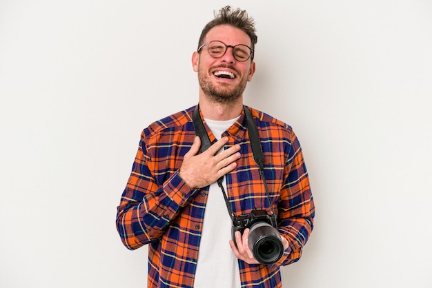 Jeune homme de photographie caucasien isolé sur fond blanc rit bruyamment en gardant la main sur la poitrine.