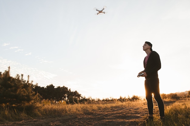 Jeune homme pilotant un drone rc en plein air