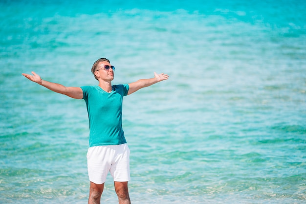 Jeune homme sur la plage blanche en vacances