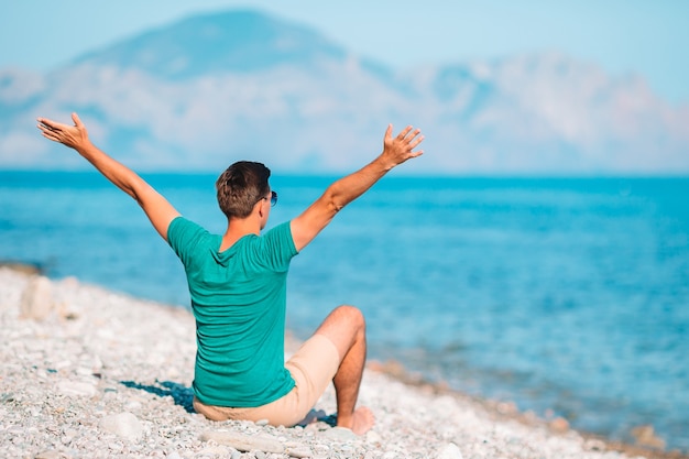 Jeune homme sur la plage blanche en vacances