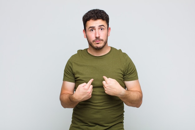 Jeune homme pointant vers soi avec un regard confus et interrogateur, choqué et surpris d'être choisi