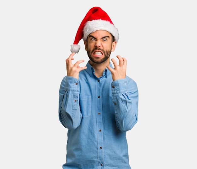 Jeune homme portant le bonnet de Noel en colère et contrarié