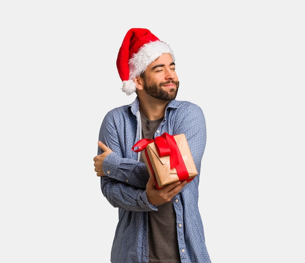 Jeune homme portant le bonnet de Noel donnant un câlin