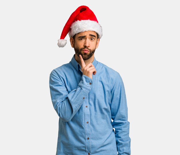 Jeune homme portant le bonnet de Noel doutant et confus