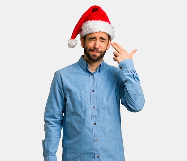 Jeune homme portant le bonnet de Noel faisant un geste de suicide