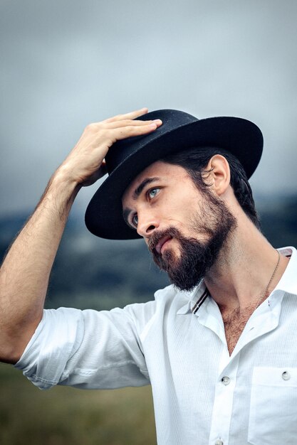 Photo un jeune homme portant un chapeau détournant le regard vers le ciel.