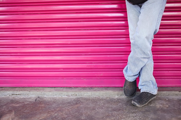 Jeune homme portant une chemise et un jean contre un mur