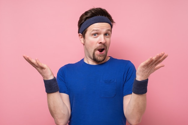 Jeune homme portant une chemise de sport choqué par une expression de surprise et un visage excité.