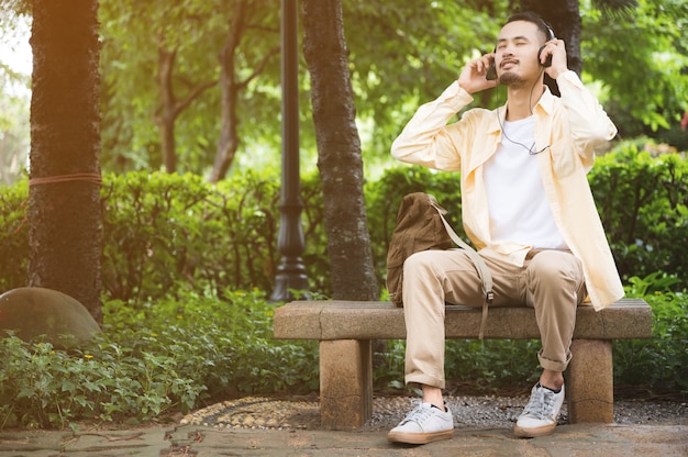 Un jeune homme portant des écouteurs et à l'aide d'une tablette dans le parc Ambiance relaxante après une horrible épidémie
