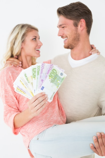 Jeune homme portant une femme joyeuse avec des billets de banque