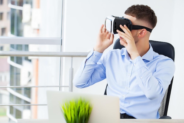 Jeune homme portant des lunettes de réalité virtuelle dans un bureau moderne.