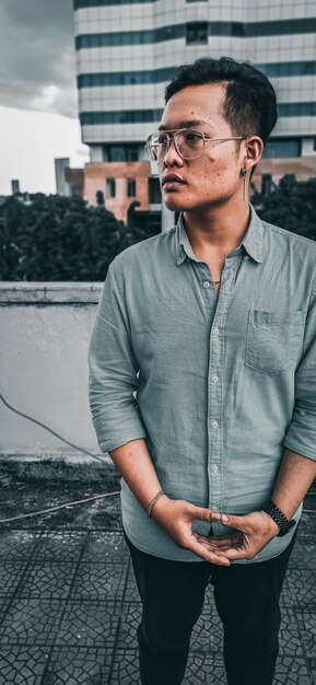 Photo un jeune homme portant des lunettes de soleil debout à l'extérieur