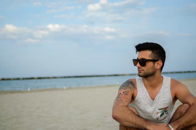 Un jeune homme portant des lunettes de soleil sur la plage contre le ciel