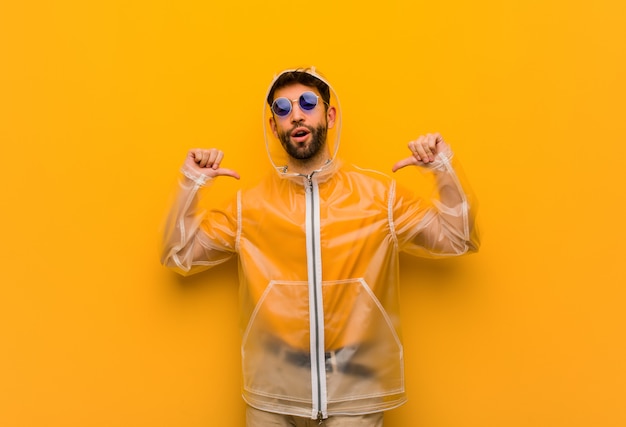 Jeune homme portant un manteau de pluie pointant les doigts, exemple à suivre