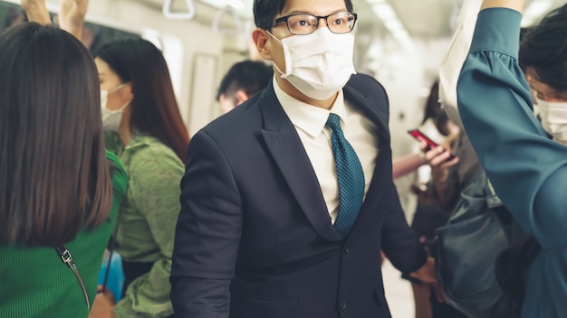 Un jeune homme portant un masque facial voyage dans une rame de métro bondée